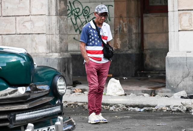 A man wearing a T-shirt with the United States flag walks down a street in Havana on March 13, 2026. Cuba's President Miguel Diaz-Canel confirmed on March 13, 2026 that “Cuban officials have recently held talks” with representatives of the United States, amid heightened tensions between Washington and Havana. (Photo by YAMIL LAGE / AFP)