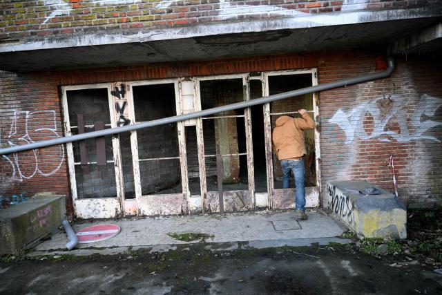 An urban explorer (urbex) walks in an abandoned public swimming pool in Charleroi, southern Belgium, on February 9, 2026. Once a major industrial city of the coal industry, Charleroi still bears the marks of a working-class past now lying fallow. As they venture through its abandoned factories, urban explorers (urbex) end up telling the story of a system as much as of a pastime: that of a capitalism which pours investment into a place, exploits it, then withdraws, leaving behind nothing but ruins to explore. (Photo by Nicolas TUCAT / AFP)