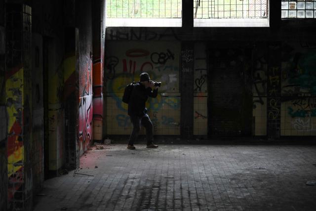 An urban explorer (urbex) takes photographs in an abandoned public swimming pool in Charleroi, southern Belgium, on March 11, 2026. Once a major industrial city of the coal industry, Charleroi still bears the marks of a working-class past now lying fallow. As they venture through its abandoned factories, urban explorers (urbex) end up telling the story of a system as much as of a pastime: that of a capitalism which pours investment into a place, exploits it, then withdraws, leaving behind nothing but ruins to explore. (Photo by Nicolas TUCAT / AFP)