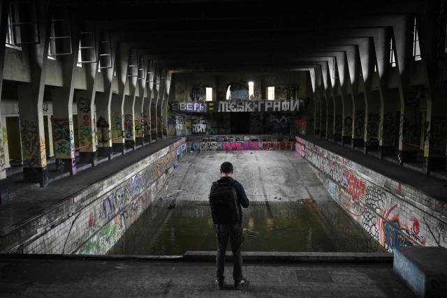 An urban explorer (urbex) scouts an abandoned public swimming pool in Charleroi, southern Belgium, on March 11, 2026. Once a major industrial city of the coal industry, Charleroi still bears the marks of a working-class past now lying fallow. As they venture through its abandoned factories, urban explorers (urbex) end up telling the story of a system as much as of a pastime: that of a capitalism which pours investment into a place, exploits it, then withdraws, leaving behind nothing but ruins to explore. (Photo by Nicolas TUCAT / AFP)