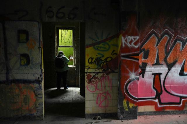 An urban explorer (urbex) takes photographs in an abandoned public swimming pool in Charleroi, southern Belgium, on March 11, 2026. Once a major industrial city of the coal industry, Charleroi still bears the marks of a working-class past now lying fallow. As they venture through its abandoned factories, urban explorers (urbex) end up telling the story of a system as much as of a pastime: that of a capitalism which pours investment into a place, exploits it, then withdraws, leaving behind nothing but ruins to explore. (Photo by Nicolas TUCAT / AFP)