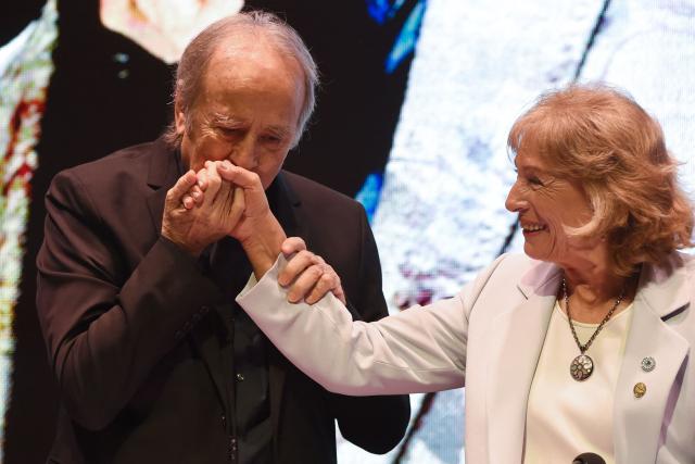 Spanish singer-songwriter Joan Manuel Serrat kisses the hand of Esther Sanchez, rector of the National University of Cuyo, while receiving an honorary doctorate during a ceremony at the Nave UNCuyo complex in Mendoza, Argentina, on March 13, 2026. (Photo by Andres Larrovere / AFP)