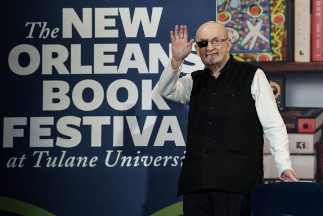 Indian-British novelist Salman Rushdie waves onstage at the New Orleans Book Festival at Tulane University in New Orleans, Louisiana, on March 13, 2026. Rushdie's latest novel, "The Eleventh Hour", released in November 2025, is his first work of fiction since a knife attack in 2022. (Photo by Matthew HINTON / AFP)