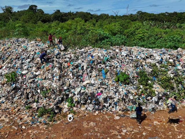 In this aerial view recyclable materials collectors search for objects at an open-air landfill in the city of Iranduba, in the state of Amazonas, northern Brazil, on March 13, 2026. The open-air dump in Iranduba is an environmental and public health crisis that has been operating illegally for 40 years, contaminating the soil and groundwater. (Photo by MICHAEL DANTAS / AFP)