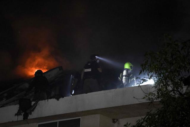 Israeli firefighters stand on the roof of a house that was reportedly hit by a projectile in Shohami, in central Israel, near Tel Aviv on March 13, 2026. Smoke could be seen rising from two locations around Israel's commercial hub Tel Aviv on March 13, AFP journalists said, after blasts were heard following a warning that missiles were fired from Iran. (Photo by Ilia YEFIMOVICH / AFP) / 