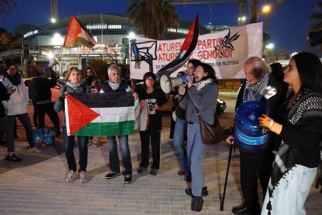 Protesters hold Paslestine flags and shout slogans during a demonstration against the participation of Israeli basketball team Hapoel IBI Tel-Aviv in the Euroleague, ahead of their match against FC Barcelona at Palau Blaugrana arena in Barcelona on March 13, 2026. (Photo by Lluis GENE / AFP)