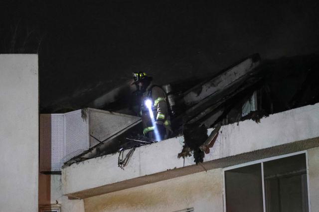 An Israeli firefighter stands on the roof of a house that was reportedly hit by a projectile in Shohami, in central Israel, near Tel Aviv on March 13, 2026. Smoke could be seen rising from two locations around Israel's commercial hub Tel Aviv on March 13, AFP journalists said, after blasts were heard following a warning that missiles were fired from Iran. (Photo by Ilia YEFIMOVICH / AFP) / 