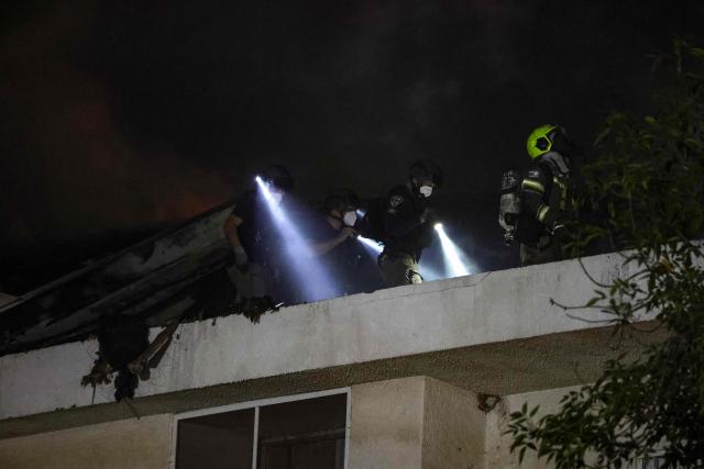 Israeli firefighters and police inspect debris on the roof of a house that was reportedly hit by a projectile in Shohami, in central Israel, near Tel Aviv on March 13, 2026. Smoke could be seen rising from two locations around Israel's commercial hub Tel Aviv on March 13, AFP journalists said, after blasts were heard following a warning that missiles were fired from Iran. (Photo by Ilia YEFIMOVICH / AFP) / 