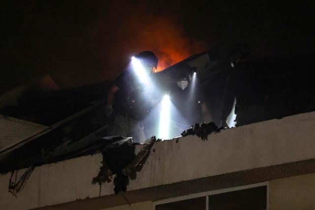 Israeli police inspect debris on the roof of a house that was reportedly hit by a projectile in Shohami, in central Israel, near Tel Aviv on March 13, 2026. Smoke could be seen rising from two locations around Israel's commercial hub Tel Aviv on March 13, AFP journalists said, after blasts were heard following a warning that missiles were fired from Iran. (Photo by Ilia YEFIMOVICH / AFP) / 