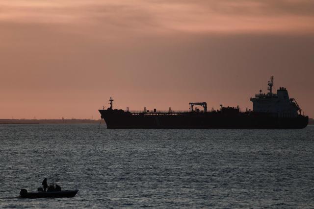 This photograph shows a small boat in front of an oil tanker anchored at the Grand Port Maritime de Marseille-Fos at sunset, in Fos-sur-Mer, off the Mediterranean coast of southern France on March 13, 2026. (Photo by Thibaud MORITZ / AFP)