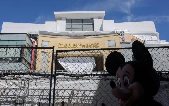 The silhouette of a street performer dressed as Mickey Mouse is seen in front of the Dolby Theatre as preparations are made ahead of the 98th Annual Academy Awards in Hollywood, California, on March 13, 2026. (Photo by ANGELA WEISS / AFP)