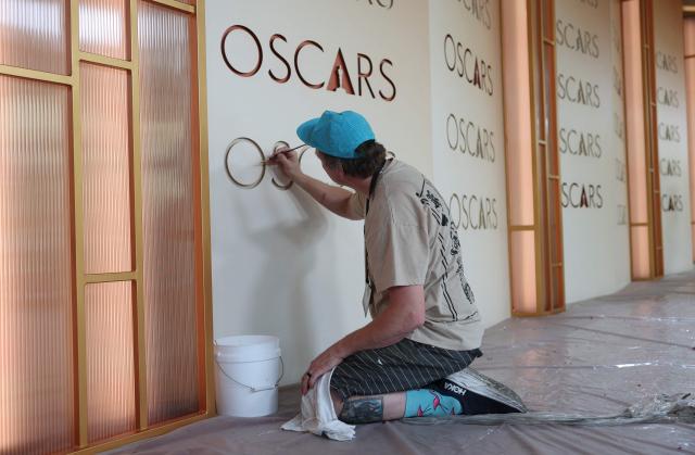 A a worker retouches the backdrop as preparations are made on the red carpet arrivals area ahead of the 98th Annual Academy Awards in Hollywood, California, on March 13, 2026. (Photo by ANGELA WEISS / AFP)