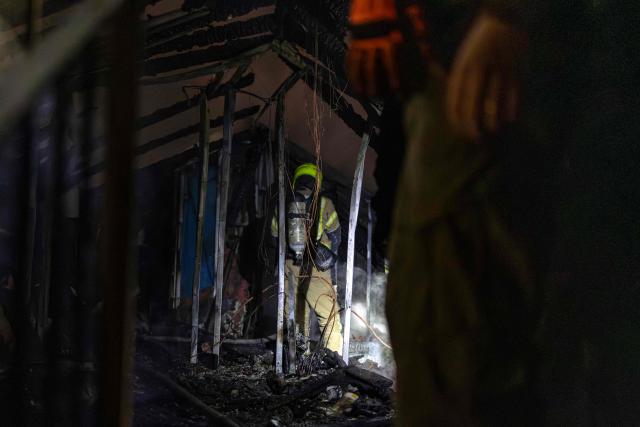 Israeli firefighters inspect the damage at a house that was reportedly hit by a projectile in Shoham  in central Israel, near Tel Aviv, on March 13, 2026. Smoke could be seen rising from two locations around Israel's commercial hub Tel Aviv on March 13, AFP journalists said, after blasts were heard following a warning that missiles were fired from Iran. (Photo by Ilia YEFIMOVICH / AFP)