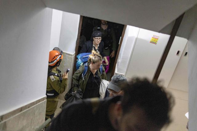 People evacuate a house that was reportedly hit by a projectile in Shoham  in central Israel, near Tel Aviv, on March 13, 2026. Smoke could be seen rising from two locations around Israel's commercial hub Tel Aviv on March 13, AFP journalists said, after blasts were heard following a warning that missiles were fired from Iran. (Photo by Ilia YEFIMOVICH / AFP) / 