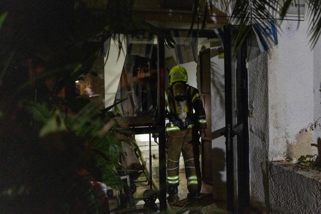 An Israeli firefighter inspects the damage at a house that was reportedly hit by a projectile in Shoham  in central Israel, near Tel Aviv, on March 13, 2026. Smoke could be seen rising from two locations around Israel's commercial hub Tel Aviv on March 13, AFP journalists said, after blasts were heard following a warning that missiles were fired from Iran. (Photo by Ilia YEFIMOVICH / AFP) / 