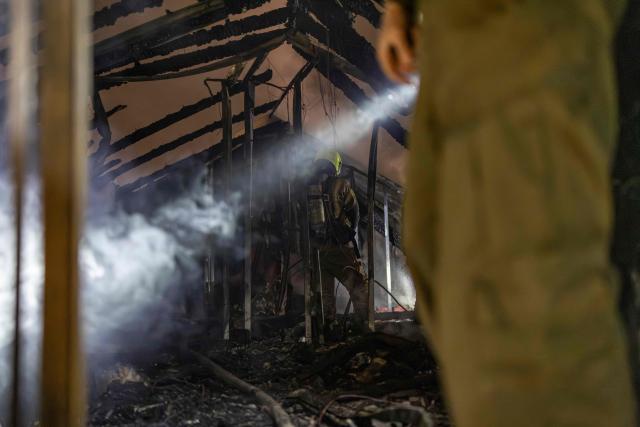 TOPSHOT - Israeli firefighters working at the house that was reportedly hit by a projectile in Shoham  in central Israel, near Tel Aviv on March 13, 2026. Smoke could be seen rising from two locations around Israel's commercial hub Tel Aviv on March 13, AFP journalists said, after blasts were heard following a warning that missiles were fired from Iran (Photo by Ilia YEFIMOVICH / AFP) / 