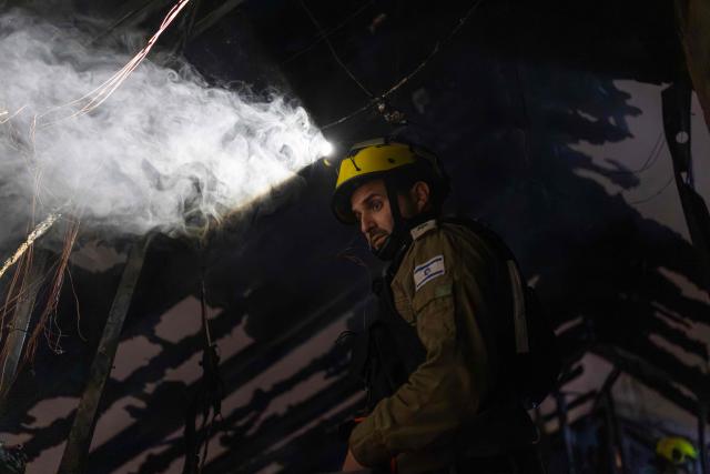 An Israeli firefighter inspects the damage at a house that was reportedly hit by a projectile in Shoham  in central Israel, near Tel Aviv, on March 13, 2026. Smoke could be seen rising from two locations around Israel's commercial hub Tel Aviv on March 13, AFP journalists said, after blasts were heard following a warning that missiles were fired from Iran. (Photo by Ilia YEFIMOVICH / AFP) / 