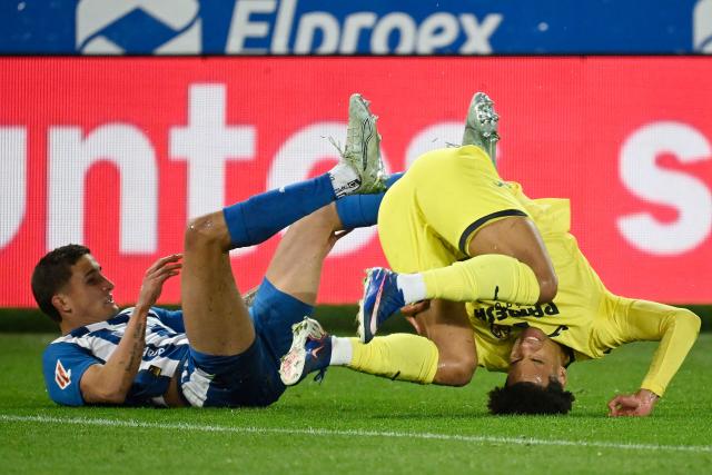 Villarreal's Canadian midfielder #17 Tajon Buchanan goes head over heels next to Alaves' Argentine defender #14 Nahuel Tenaglia (L) during the Spanish League football match between Deportivo Alaves and Villarreal CF at Mendizorroza Stadium in Vitoria on March 13, 2026. (Photo by ANDER GILLENEA / AFP)