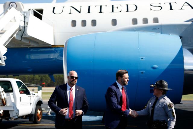 US Vice President JD Vance (C) speaks to a member of law enforcement as he prepares to board Air Force Two as he returns to Washington, DC at Rocky Mount-Wilson Regional Airport on March 13, 2026 in Elm City, North Carolina. Vance traveled to North Carolina to deliver remarks on the Trump administration's economic agenda. (Photo by Kent Nishimura / POOL / AFP)