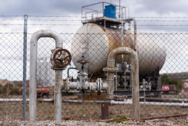 Rusted pipes, hand-valves are seen with a weathered storage tank in the background at an obsolete oil field in Sargentes de la Lora on March 13, 2026, near Burgos in northern Spain, where oil first flowed in Spain in 1964. Spain's leftist government yesterday said it would soon present a plan to contain the Middle East war's impact on electricity and fuel prices in one of the most dynamic developed economies. The closure of the Strait of Hormuz, a vital waterway for oil and gas exports from the energy-rich Gulf, following the US-Israeli strikes on Iran from February 28 has roiled world energy markets. (Photo by Cesar MANSO / AFP)