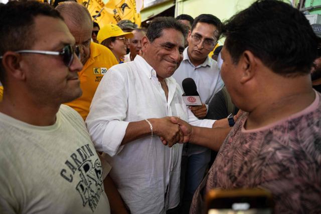 Peru's presidential candidate Carlos Alvarez, for the Pais Para Todos party, greets a man as he visit a market in the Ventanilla district on the southern outskirts of Lima on March 13, 2026. (Photo by ERNESTO BENAVIDES / AFP)