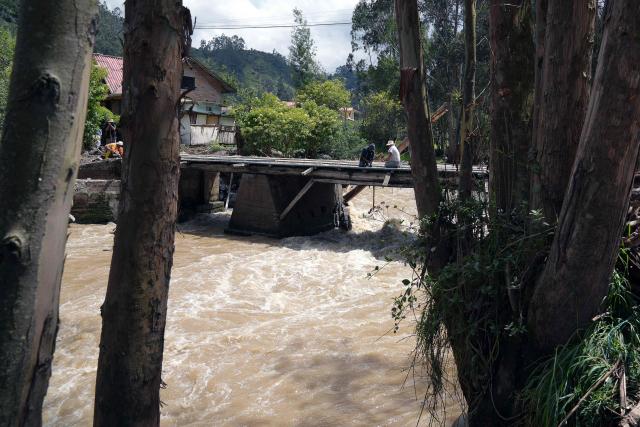 Locals repair a bridge after the Yanuncay River swelled in the Barabon area of Cuenca, Ecuador, on March 13, 2026. Ecuador declared a 60-day national emergency to confront an intense rainy season that has left 11 people dead and thousands affected since January, the government disaster management agency said on March 13. (Photo by Fernando Machado / AFP)