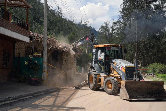 A backhoe works on a house affected by the overflowing Yanuncay River in the Barabon area of Cuenca, Ecuador, on March 13, 2026. Ecuador declared a 60-day national emergency to confront an intense rainy season that has left 11 people dead and thousands affected since January, the government disaster management agency said on March 13. (Photo by Fernando Machado / AFP)