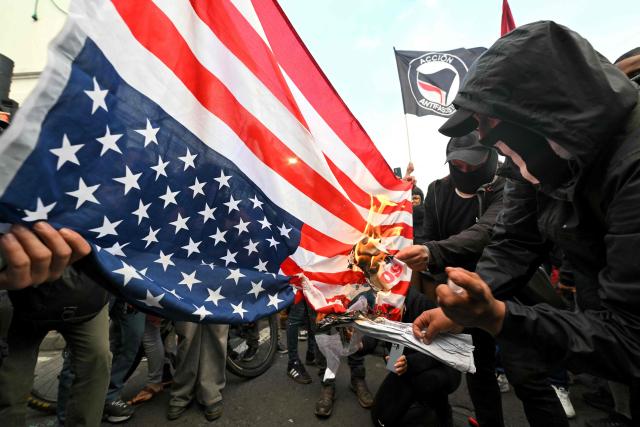 Demonstrators set fire to a United States flag during a march against the government called by unions in Quito on March 13, 2026. (Photo by Rodrigo BUENDIA / AFP)