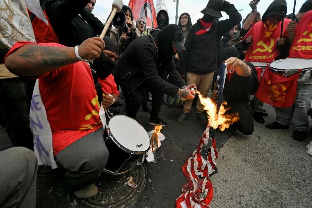 Demonstrators set fire to a United States flag during a march against the government called by unions in Quito on March 13, 2026. (Photo by Rodrigo BUENDIA / AFP)