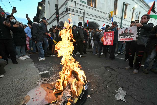 Demonstrators surroind a burning pile of trash during a march against the government called by unions in Quito on March 13, 2026. (Photo by Rodrigo BUENDIA / AFP)