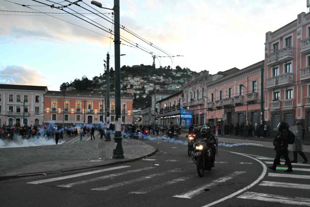 Demonstrators return a tear gas canister to riot police officers as they clash during a march against the government called by unions in Quito on March 13, 2026. (Photo by Rodrigo BUENDIA / AFP)