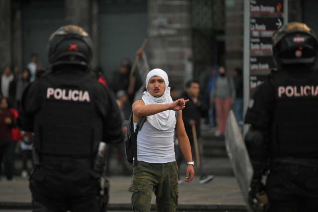 A demonstrator gestures in front of riot police officers during a march against the government called by unions in Quito on March 13, 2026. (Photo by Rodrigo BUENDIA / AFP)