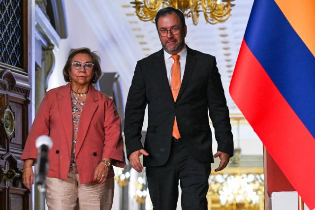 Colombia's Foreign Minister Rosa Yolanda Villavicencio (L) and Venezuela's Foreign Minister Yvan Gil (R) walk out of a meeting with interim President Delcy Rodriguez at the Miraflores Presidential Palace in Caracas on March 13, 2026. Venezuela met with a Colombian high-level delegation on March 13, 2026, after the Venezuelan government announced the previous day that a meeting between the presidents of both countries, which was to take place at a border bridge, had been canceled. (Photo by Juan BARRETO / AFP)