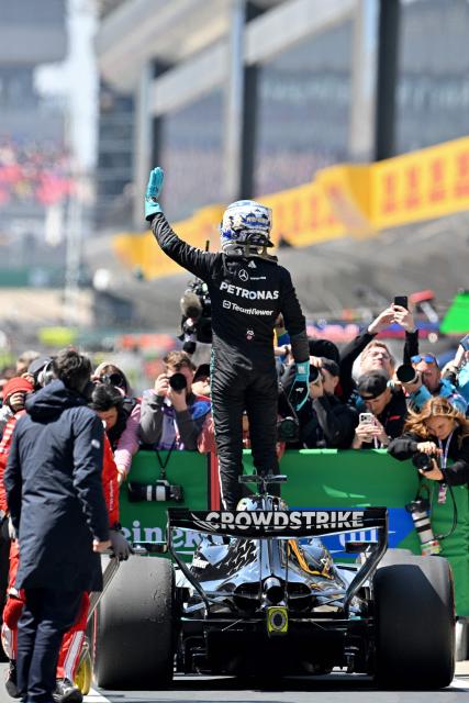 Mercedes' British driver George Russell stands over his car as he celebrates winning the sprint race ahead of the Formula One Chinese Grand Prix at the Shanghai International Circuit in Shanghai on March 14, 2026. (Photo by HECTOR RETAMAL / AFP)