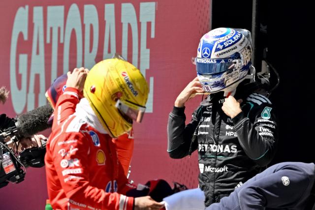 Mercedes' British driver George Russell (R) gestures in the pit lane after winning the sprint race ahead of the Formula One Chinese Grand Prix at the Shanghai International Circuit in Shanghai on March 14, 2026. (Photo by HECTOR RETAMAL / AFP)