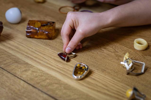 Student of the Experimental Design Studio looks on pieces of jewellery design and created by other students on Academy of Fine Arts in Gdansk, Poland on March 10, 2026. Long coveted for its golden color, scientific value and alleged healing properties, amber is now coming into the hand of young Polish jewelers, bringing the ancient resin into modern times. Together with drills, sanders, blasters, and power saws which look like they belong to a bygone era, virtual reality stations are used to combine earlier tools with state-of-the-art technology at the Academy of Fine Arts in Gdansk, a city on Poland's Baltic Coast known as amber's global capital. (Photo by Wojtek RADWANSKI / AFP)