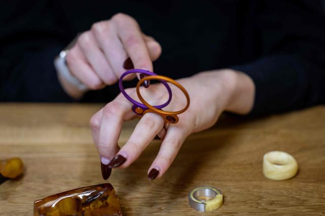 Student of the Experimental Design Studio looks on pieces of jewellery design and created by other students on Academy of Fine Arts in Gdansk, Poland on March 10, 2026. Long coveted for its golden color, scientific value and alleged healing properties, amber is now coming into the hand of young Polish jewelers, bringing the ancient resin into modern times. Together with drills, sanders, blasters, and power saws which look like they belong to a bygone era, virtual reality stations are used to combine earlier tools with state-of-the-art technology at the Academy of Fine Arts in Gdansk, a city on Poland's Baltic Coast known as amber's global capital. (Photo by Wojtek RADWANSKI / AFP)