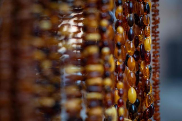 This photo shows necklaces made from natural Baltic amber, on sale at a street stall on Mariacka Street in Gdansk, Poland on March 10, 2026. Long coveted for its golden color, scientific value and alleged healing properties, amber is now coming into the hand of young Polish jewelers, bringing the ancient resin into modern times. Together with drills, sanders, blasters, and power saws which look like they belong to a bygone era, virtual reality stations are used to combine earlier tools with state-of-the-art technology at the Academy of Fine Arts in Gdansk, a city on Poland's Baltic Coast known as amber's global capital. (Photo by Wojtek RADWANSKI / AFP)