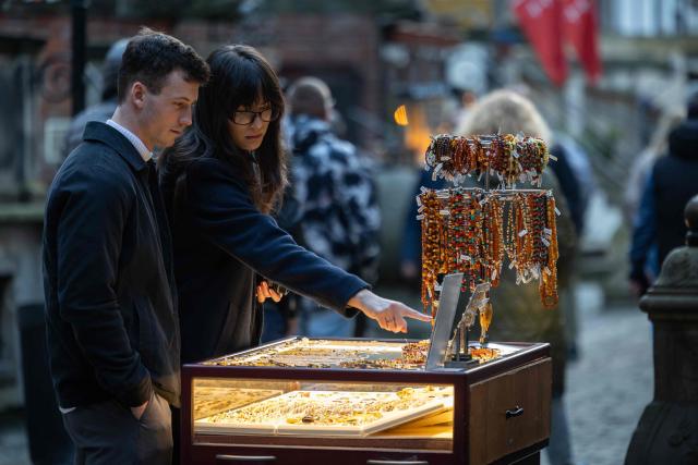 A couple looks on necklaces and other jewellery made from natural Baltic amber offered at a stall outside the amber shop on Mariacka Street in Gda?sk, Poland on March 10, 2026. Long coveted for its golden color, scientific value and alleged healing properties, amber is now coming into the hand of young Polish jewelers, bringing the ancient resin into modern times. Together with drills, sanders, blasters, and power saws which look like they belong to a bygone era, virtual reality stations are used to combine earlier tools with state-of-the-art technology at the Academy of Fine Arts in Gdansk, a city on Poland's Baltic Coast known as amber's global capital. (Photo by Wojtek RADWANSKI / AFP)