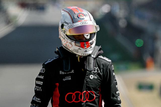 Audi's German driver Nico Hulkenberg walks after stopping his car during the sprint race ahead of the Formula One Chinese Grand Prix at the Shanghai International Circuit in Shanghai on March 14, 2026. (Photo by Greg Baker / AFP)