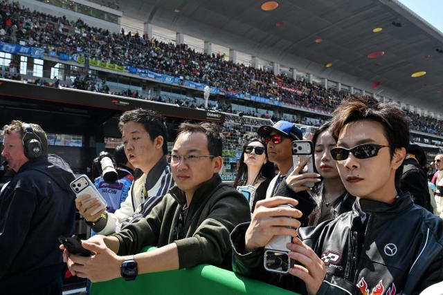 Fans take photos of the pit lane after the sprint race ahead of the Formula One Chinese Grand Prix at the Shanghai International Circuit in Shanghai on March 14, 2026. (Photo by GREG BAKER / AFP)