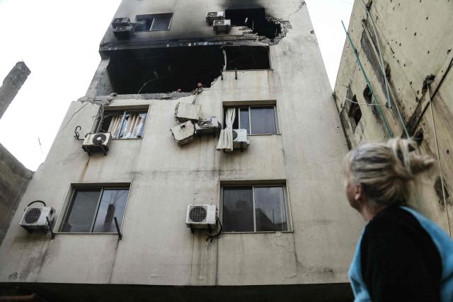 A woman looks at a building where an apartment was targeted by an Israeli airstrike in the Burj Hammoud area on the northern outskirts of Beirut on March 14, 2026. Lebanon was drawn into the Middle East war last week when Iran-backed militant group Hezbollah attacked Israel in response to the killing of the Iranian supreme leader during US-Israeli strikes. (Photo by IBRAHIM AMRO / AFP)
