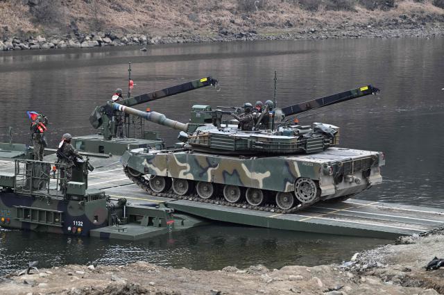 A South Korean K1A2 tank crosses a river over a floating bridge as they participate in a combined maneuver training with wet gap crossing during the 2026 South Korea-US Freedom Shield military exercise in Yeoncheon on March 14, 2026. (Photo by Jung Yeon-je / AFP)
