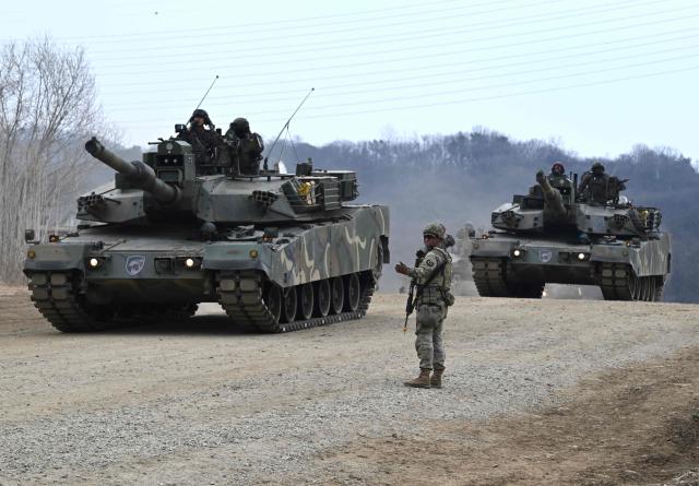 A US soldier stands in front of South Korean K1A2 tanks as they participate in a combined maneuver training with wet gap crossing during the 2026 South Korea-US Freedom Shield military exercise in Yeoncheon on March 14, 2026. (Photo by Jung Yeon-je / AFP)