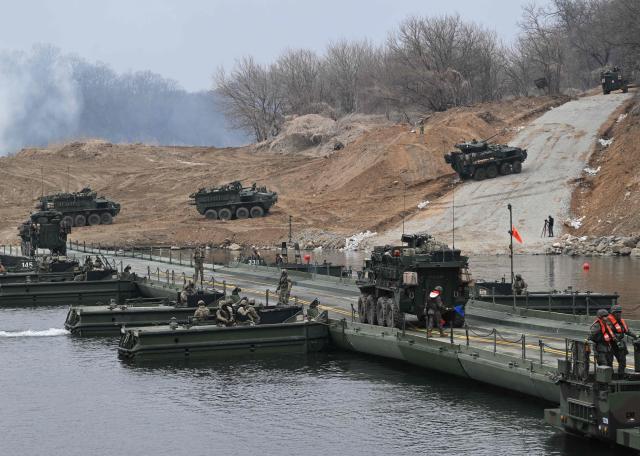 US Stryker infantry carrier vehicles cross a river over a floating bridge as they participate in a combined maneuver training with wet gap crossing during the 2026 South Korea-US Freedom Shield military exercise in Yeoncheon on March 14, 2026. (Photo by Jung Yeon-je / AFP)