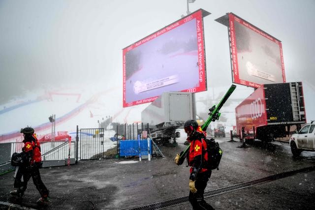 Skiers walk by giant screens announcing the cancellation of the men's Super-G event during the FIS Ski World Cup 2025-2026 in Courchevel in the French Alps on March 14, 2026. The men's world cup super-G event at Courchevel has been postponed due to heavy snow and fog, the International Ski Federation said on Marchc 14, 2026. (Photo by OLIVIER CHASSIGNOLE / AFP)