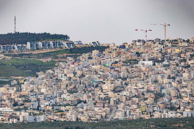 An Arab village and new housing are seen on a hilltop from the opposite Mount Tabor, northern-central Israel on March 14, 2026. Galilee is a mountainous, fertile region in northern Israel bordered by the Jordan Valley and the Mediterranean. (Photo by Odd ANDERSEN / AFP)