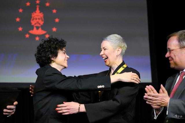 Belarusian street protest leader and activist Maria Kolesnikova (C) reacts with her sister Tatiana Khomich as CDU politician and MP Armin Laschet (R) looks on during the ceremony for the 2022 International Charlemagne Prize of Aachen (Karlspreis) at the Coronation Hall of the Town Hall in Aachen, western Germany on March 14, 2026. Kolesnikova was belatedly awarded with the 2022 International Charlemagne Prize of Aachen due to her political imprisonment in Belarus. She was released on December 13, 2025 along with 122 other prisoners after more than five years in prison for opposing Belarus's President Lukashenko. (Photo by INA FASSBENDER / AFP)
