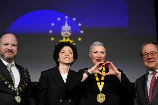 Belarusian street protest leader and activist Maria Kolesnikova (2R) reacts next to her sister Tatiana Khomich (2L), CDU politician and MP Armin Laschet (R) and Aachen Mayor Michael Ziemons (L) during the ceremony for the 2022 International Charlemagne Prize of Aachen (Karlspreis) at the Coronation Hall of the Town Hall in Aachen, western Germany on March 14, 2026. Kolesnikova was belatedly awarded with the 2022 International Charlemagne Prize of Aachen due to her political imprisonment in Belarus. She was released on December 13, 2025 along with 122 other prisoners after more than five years in prison for opposing Belarus's President Lukashenko. (Photo by INA FASSBENDER / AFP)