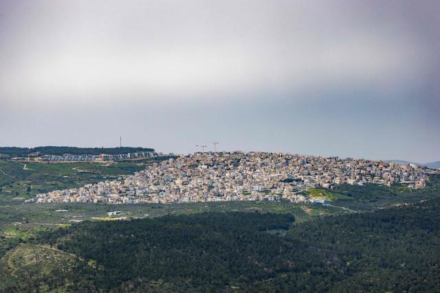 An Arab-Israeli village and new housing are seen on a hilltop from the opposite Mount Tabor, northern-central Israel on March 14, 2026. Galilee is a mountainous, fertile region in northern Israel bordered by the Jordan Valley and the Mediterranean. (Photo by Odd ANDERSEN / AFP)